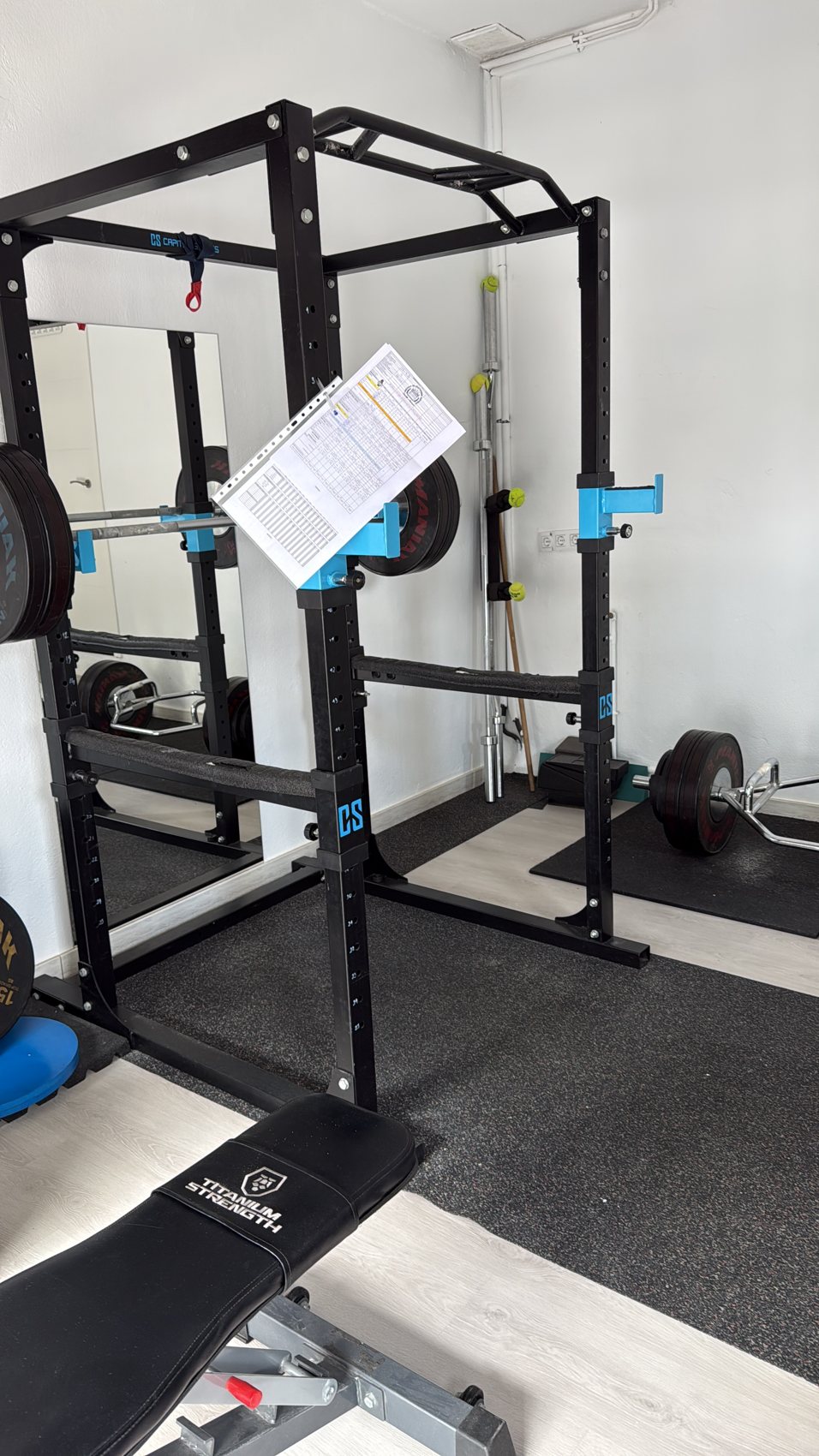 Rack de fuerza con una hoja de rutina preparada para entrenar